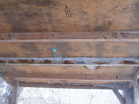 1988 Ford Bronco - The underside of a wooden structure is covered in numerous names and messages written in marker.