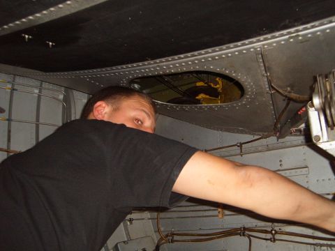 1988 Ford Bronco - Man inspects the interior of an aircraft, with visible ducting and wiring behind a metal panel.