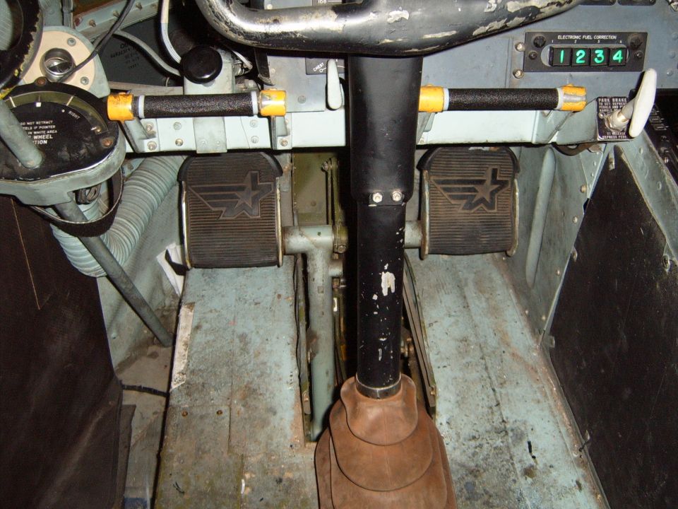Cockpit interior showing pedals, steering column, and fuel correction display