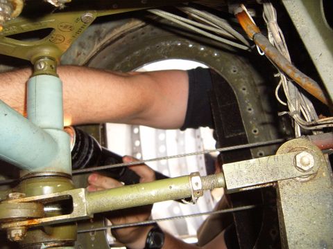 1988 Ford Bronco - Close-up of a mechanic's hands working on complex machinery inside an aircraft, illuminated by a flashlight.