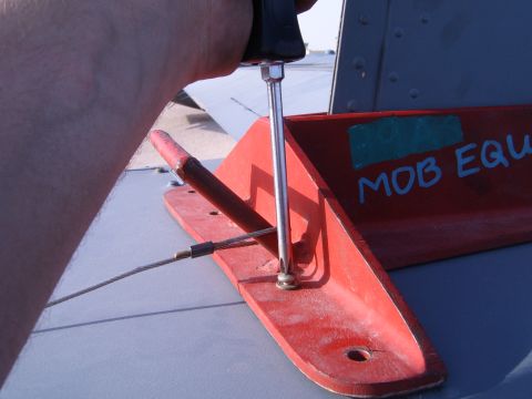 1988 Ford Bronco - Attaching a red metal bracket with a screwdriver, a cable is connected to it.