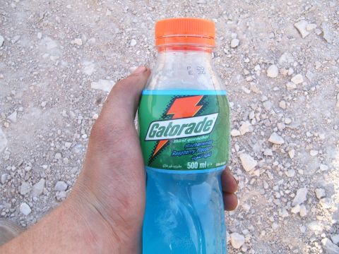 1988 Ford Bronco - A hand holds a bottle of blue raspberry Gatorade against a backdrop of gravel and dirt.