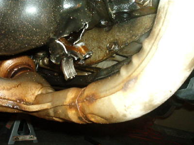 1994 Mazda MX-3 - Damage to the undercarriage and exhaust system is visible, with a bent pipe and torn metal components.