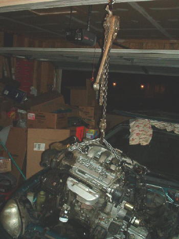 1994 Mazda MX-3 - Engine removal in progress, suspended by a chain hoist in a garage setting.