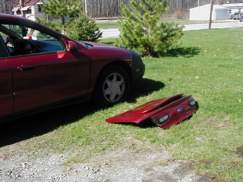 1997 Ford Taurus - A red 1997 Ford Taurus is parked on grass next to its removed deck lid and taillights.