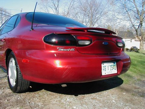 1997 Ford Taurus - The rear of a red 1997 Ford Taurus GL sedan is shown, tinted taillights and a spoiler.