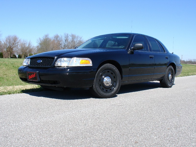 Black Ford Crown Victoria sedan, 3/4 front view, with steel wheels and DARE plate