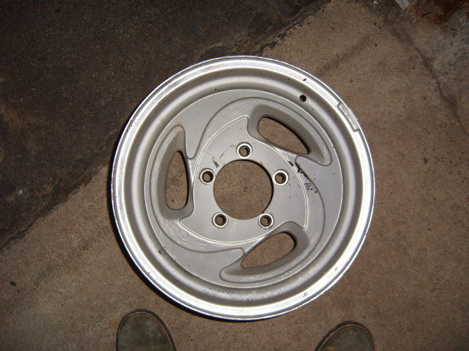 Silver aluminum wheel with five lug holes and a swirling spoke design