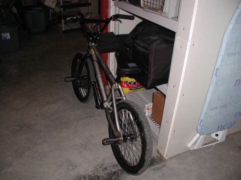 1998 Jeep TJ - A bicycle is parked indoors next to storage shelves and an ironing board.