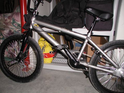 1998 Jeep TJ - A silver BMX bike is parked indoors, with a yellow bag and other items in the background.