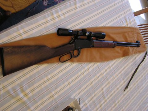2000 Chevrolet Tahoe - A rifle with a scope is laid out on a table covered with a striped cloth.