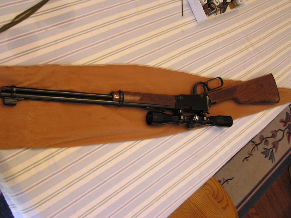 Rifle with scope on a brown cloth on a striped surface