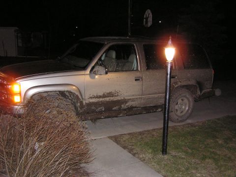 2000 Chevrolet Tahoe - This muddy 2000 Chevrolet Tahoe is seen parked at night, with its headlights on.