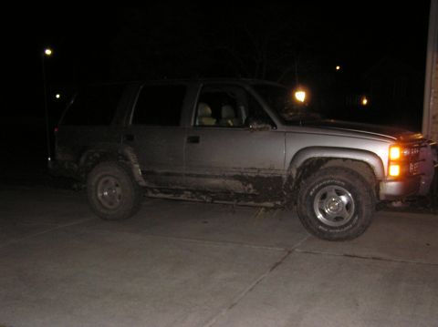 2000 Chevrolet Tahoe - A dirty SUV sits on a concrete surface at night, illuminated by streetlights.