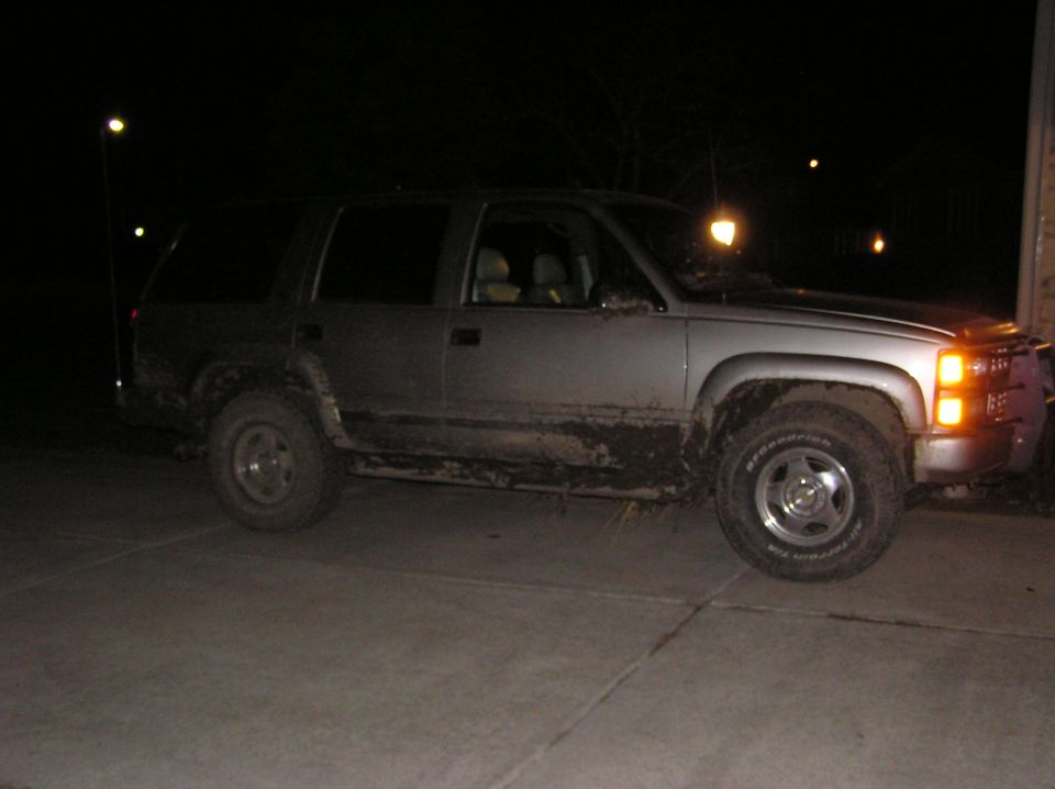 Silver Chevy Tahoe at night on a driveway, rockers caked in mud, BFG AT tires