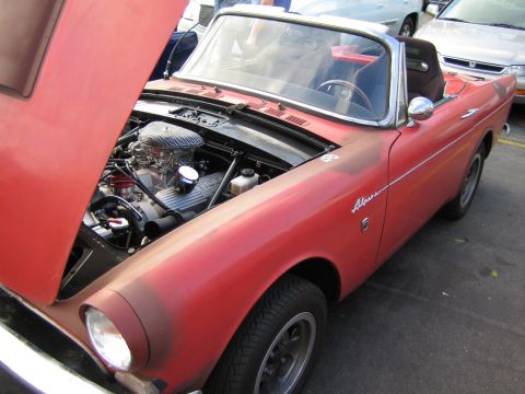 1968 Ford Mustang - A red convertible sports car with its hood open, revealing the engine compartment.