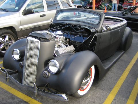 1968 Ford Mustang - A custom hot rod is parked outdoors, showing its engine and unique body style.