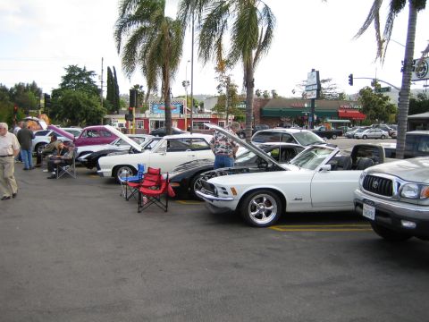 1968 Ford Mustang - A white convertible with its hood up is displayed at an outdoor car show, alongside other vehicles.