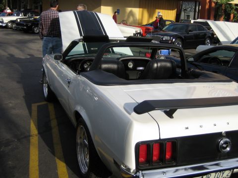 1968 Ford Mustang - A white convertible with racing stripes and a rear spoiler is parked at an outdoor car show.