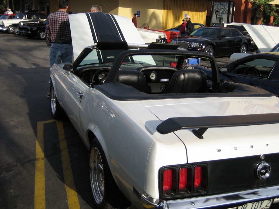 White convertible with black stripes on hood, black interior, and spoiler. Other cars parked nearby