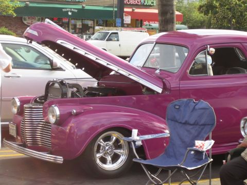 1968 Ford Mustang - A purple vintage car is displayed with its hood open, parked alongside a white van in front of a store.