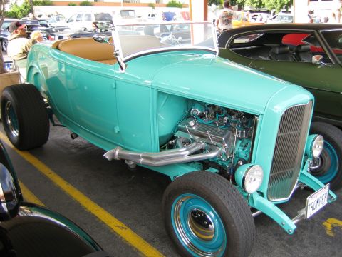 1968 Ford Mustang - A turquoise hot rod with a visible engine and custom exhaust sits in a parking lot.