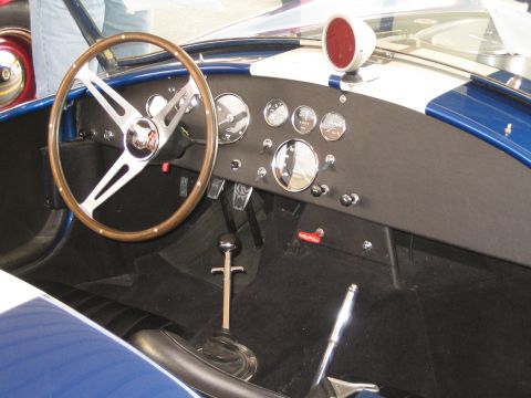 1968 Ford Mustang - The interior of a classic car shows a wooden steering wheel and a dashboard with several gauges.