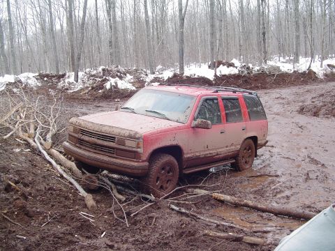 2000 Chevrolet Tahoe - This red 1995 Chevrolet Tahoe is deeply stuck in thick mud and branches in a wooded area.