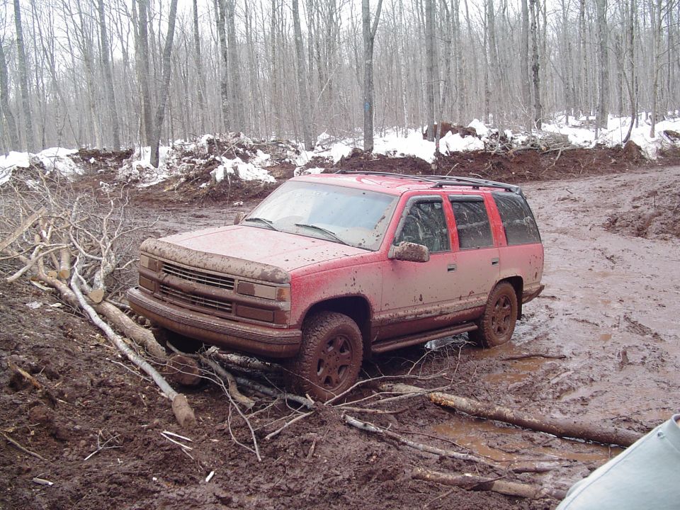 Red 1995 Chevrolet Tahoe stuck in mud, front 3/4 view