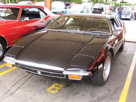 1968 Ford Mustang - A black De Tomaso Pantera is parked next to a red muscle car.