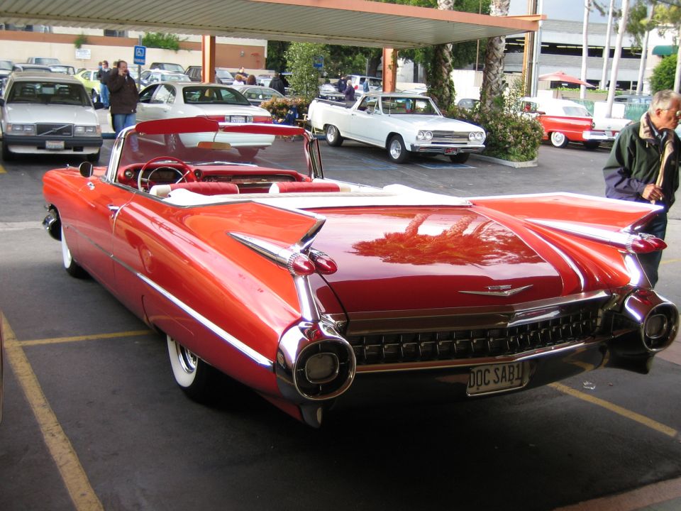 Red convertible with white top and fins, chrome accents, and whitewall tires. License plate reads DOC SAB1