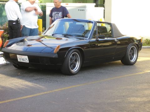 1968 Ford Mustang - A black Porsche 914 is parked on asphalt with a yellow line.