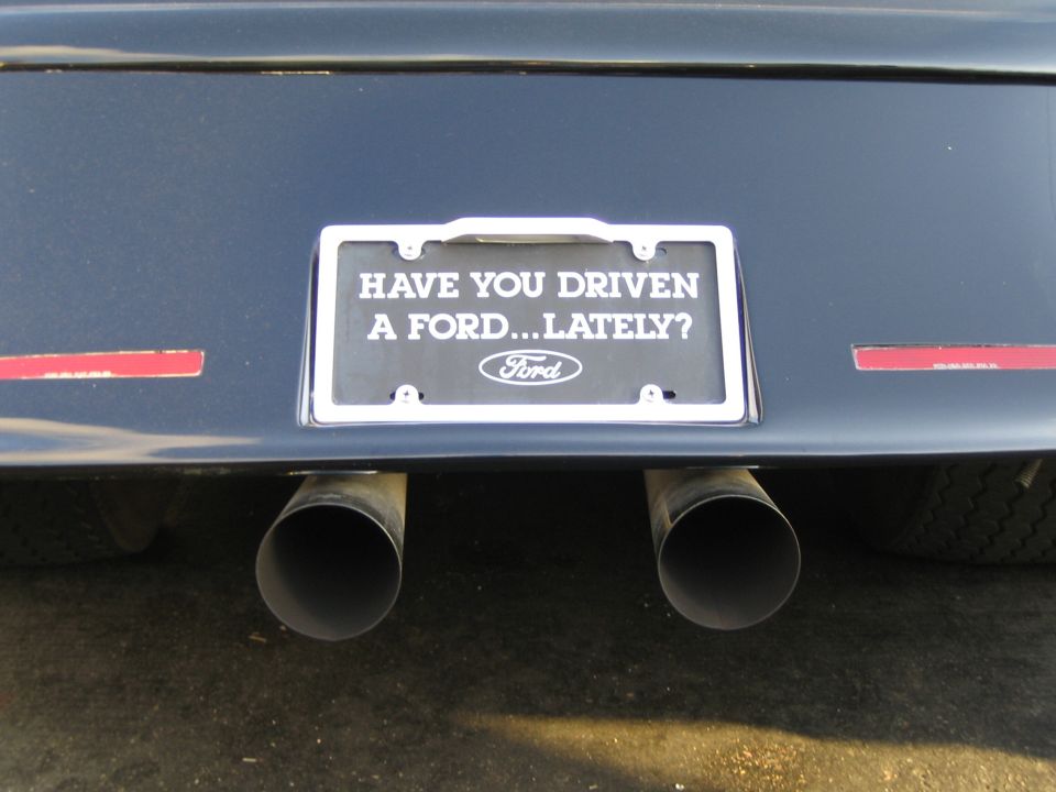 Rear view of car with dual exhaust and "HAVE YOU DRIVEN A FORD...LATELY?" license plate frame