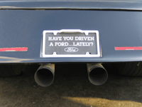 1990 Ford Bronco - Close-up of a vehicle's rear bumper with a Have You Driven a Ford Lately license plate frame mounted above two chrome exhaust tips.