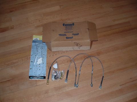 1989 Ford Bronco - New brake lines and associated hardware are laid out on a wooden floor, ready for installation.