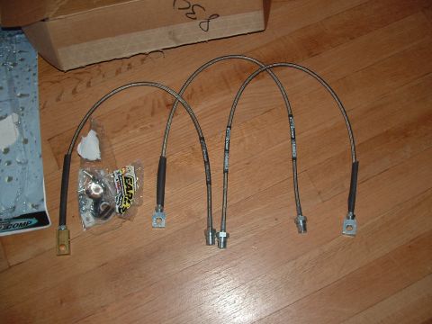 1989 Ford Bronco - Braided stainless steel brake lines are laid out on a wooden surface next to a cardboard box.
