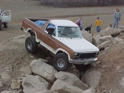 1981 Ford Bronco - A modified Ford Bronco navigates a rocky obstacle course with spectators nearby.