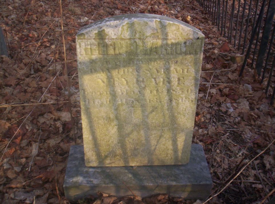 Gravestone with weathered inscriptions in a cemetery setting