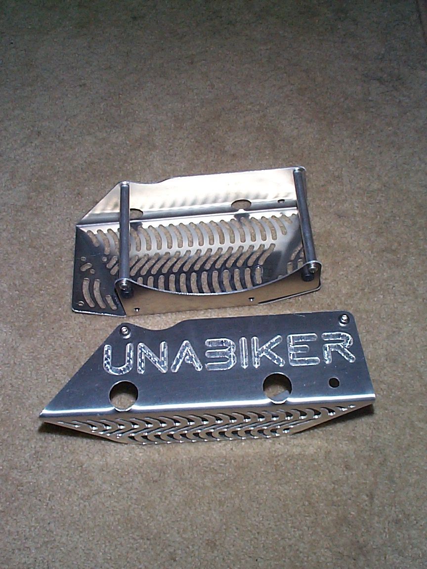 Two aluminum skid plates, one with 'UNABIKER' etched on it