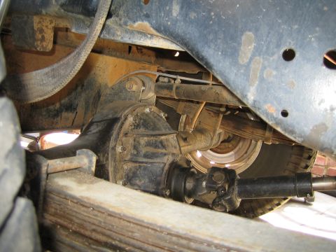1990 Ford Bronco - Undercarriage shot of a solid rear axle with differential housing, driveshaft, and leaf spring on a vehicle.