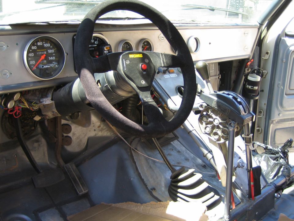 Race cockpit with Momo suede wheel, large tach, exposed steering, and shifters
