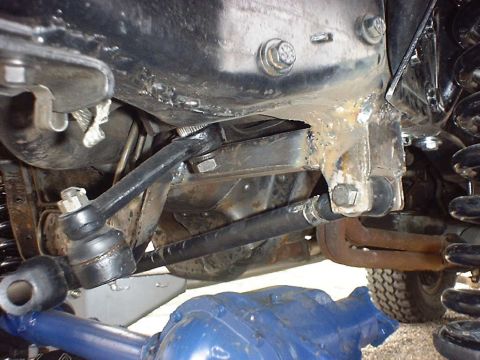 1988 Ford Bronco - Undercarriage view showing suspension parts and steering linkage, with a partial tire and differential visible.