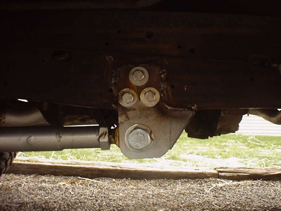 Close-up of a suspension component with multiple bolts attached to a frame