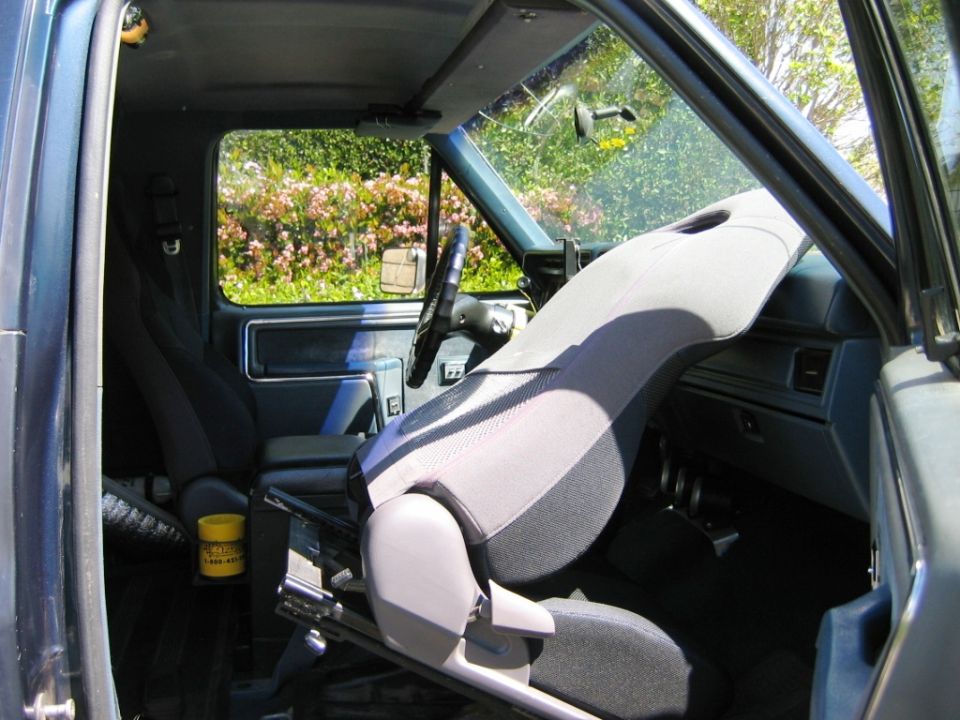 Interior of vehicle with gray cloth seat, blue dash and door panel, steering wheel visible.