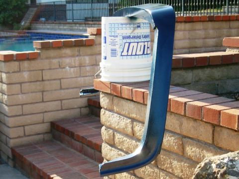 1985 Ford Bronco - A blue metal pipe and a bucket of laundry detergent are placed on brick steps next to a swimming pool.