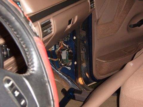 1993 Ford Bronco - View across a tan truck interior from the driver's seat, past a red-laced steering wheel cover and cruise-control spokes, to the passenger…
