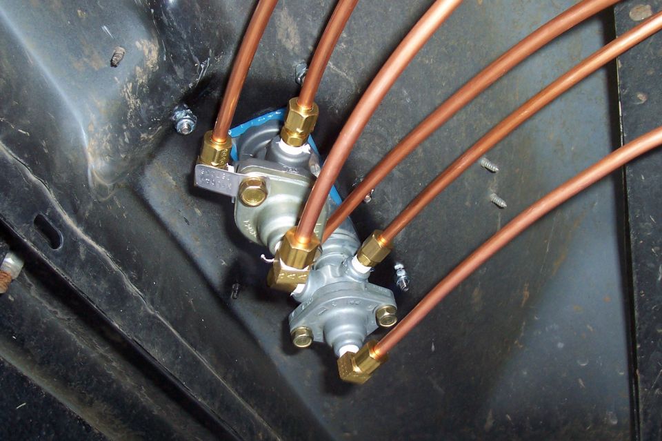 Pair of air brake valves plumbed with copper lines and brass fittings on black panel