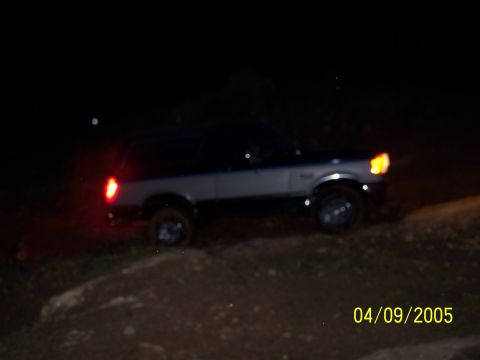 1979 Ford F-150 - Ford Bronco with its lights on at night, parked on uneven terrain.