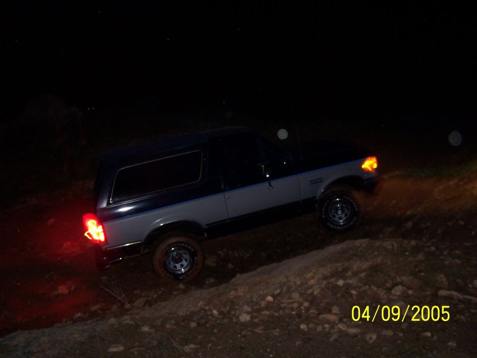 Two-tone Ford Bronco driving off-road at night