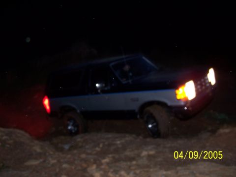 1979 Ford F-150 - A two-tone Ford Bronco navigates rough terrain in the dark.